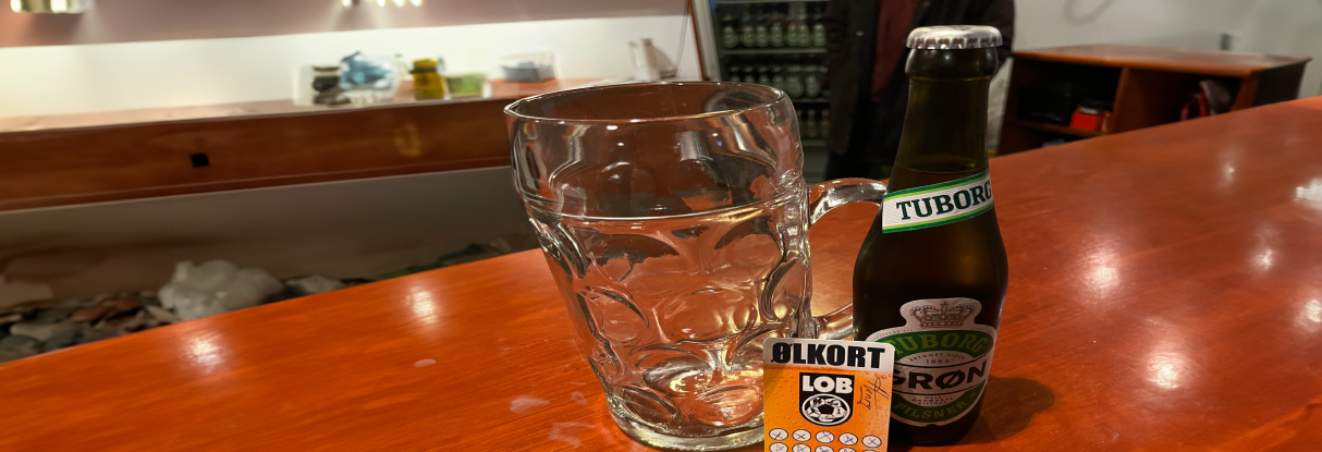 En Tuborg og et glas placeret på et bord